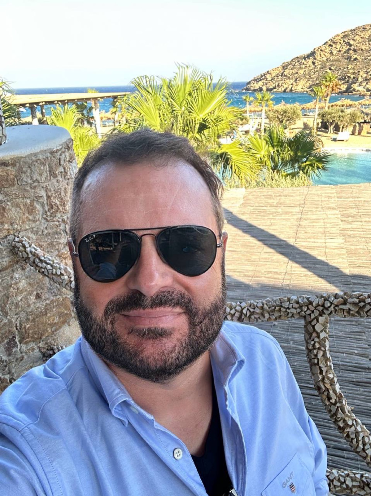Kev wearing sunglasses on a sunny terrace above the sea