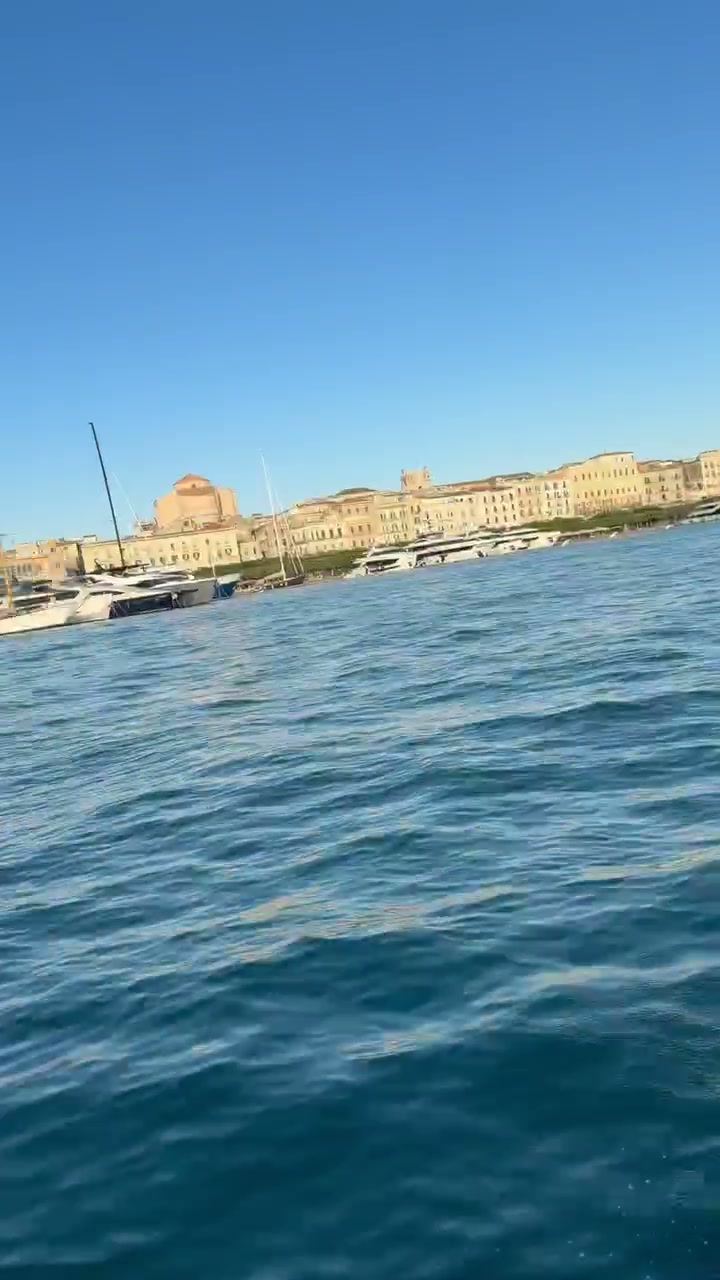 Evening light on the Ortigia waterfront seen from the water, with motor yachts berthed alongside
