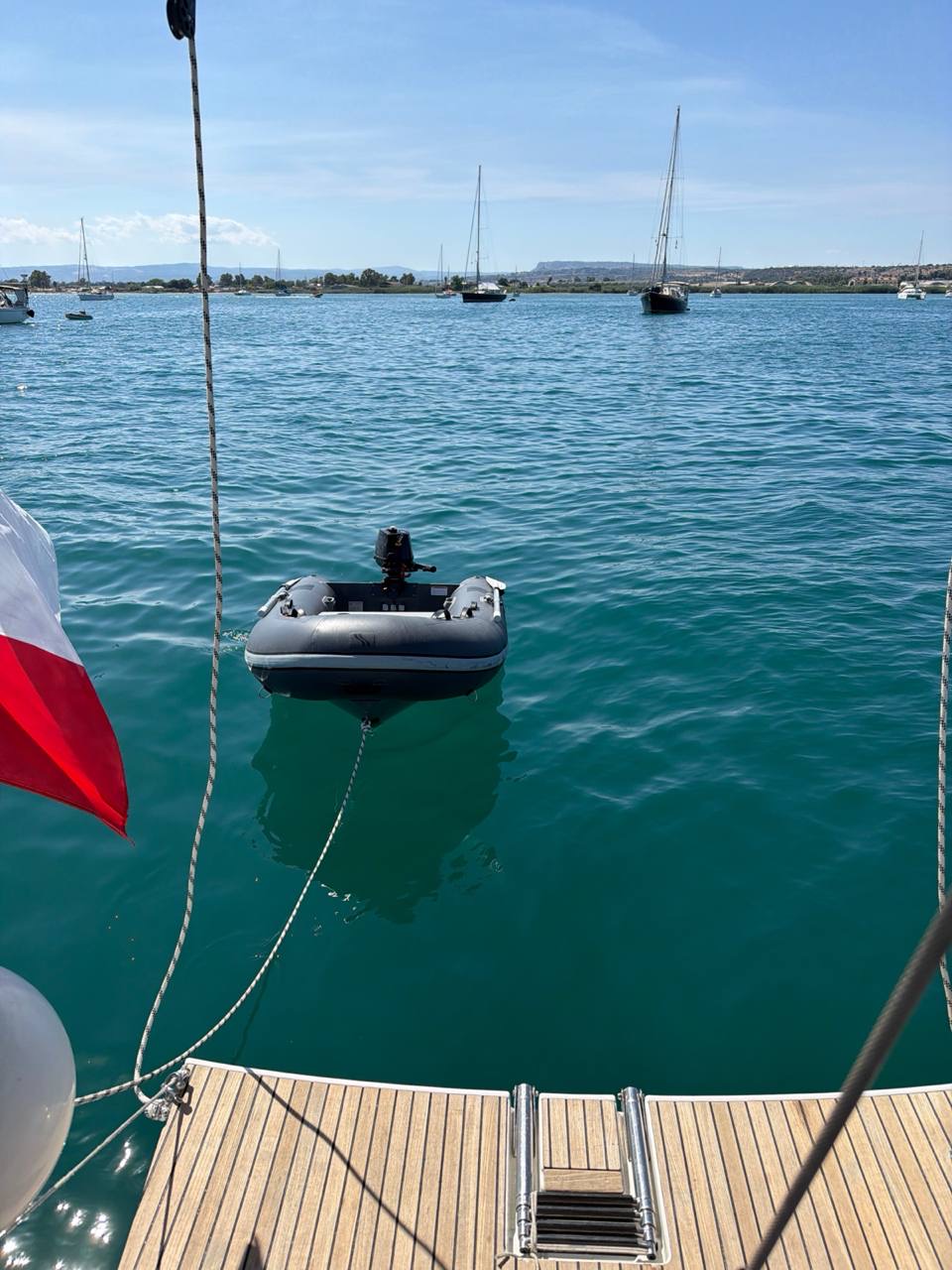 Everything Zen anchored in a calm Siracusa bay with the dinghy astern and other boats nearby